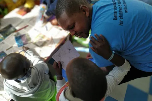 Black man in blue t-shirt engaging with children with cancer