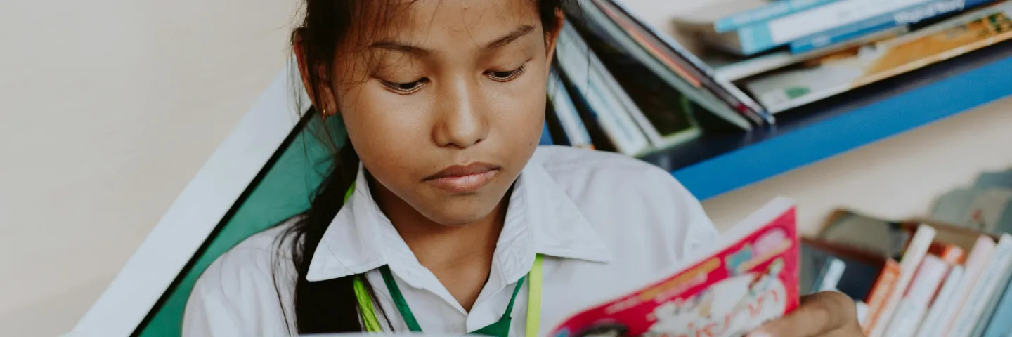 Young thai girl reads a book in school uniform