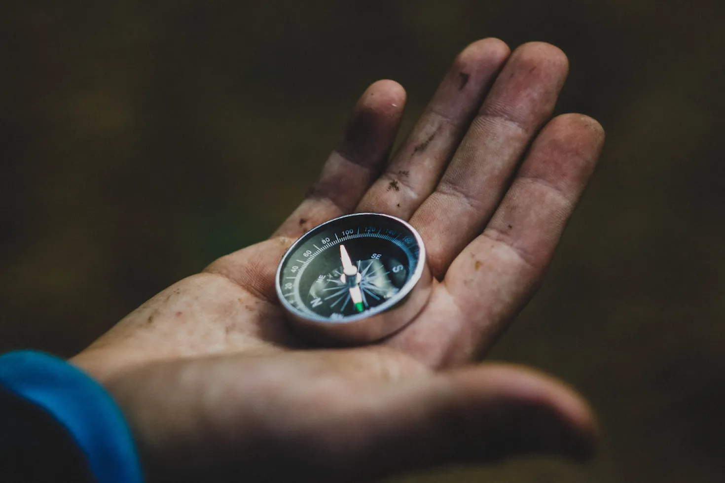 A compass held in a dirty hand