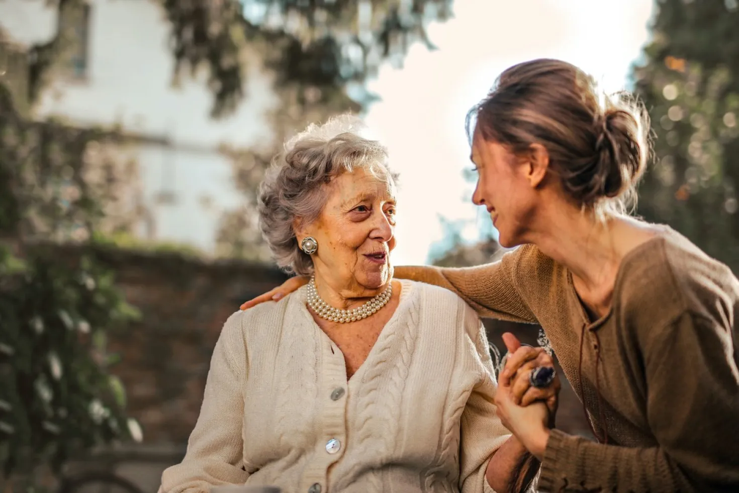 An older white woman smiling at her daughter as they hold hands