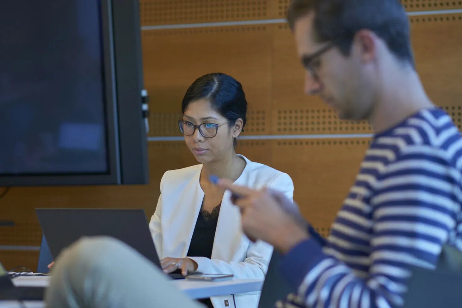 Woman working on her computer with a man looking at his smartphone