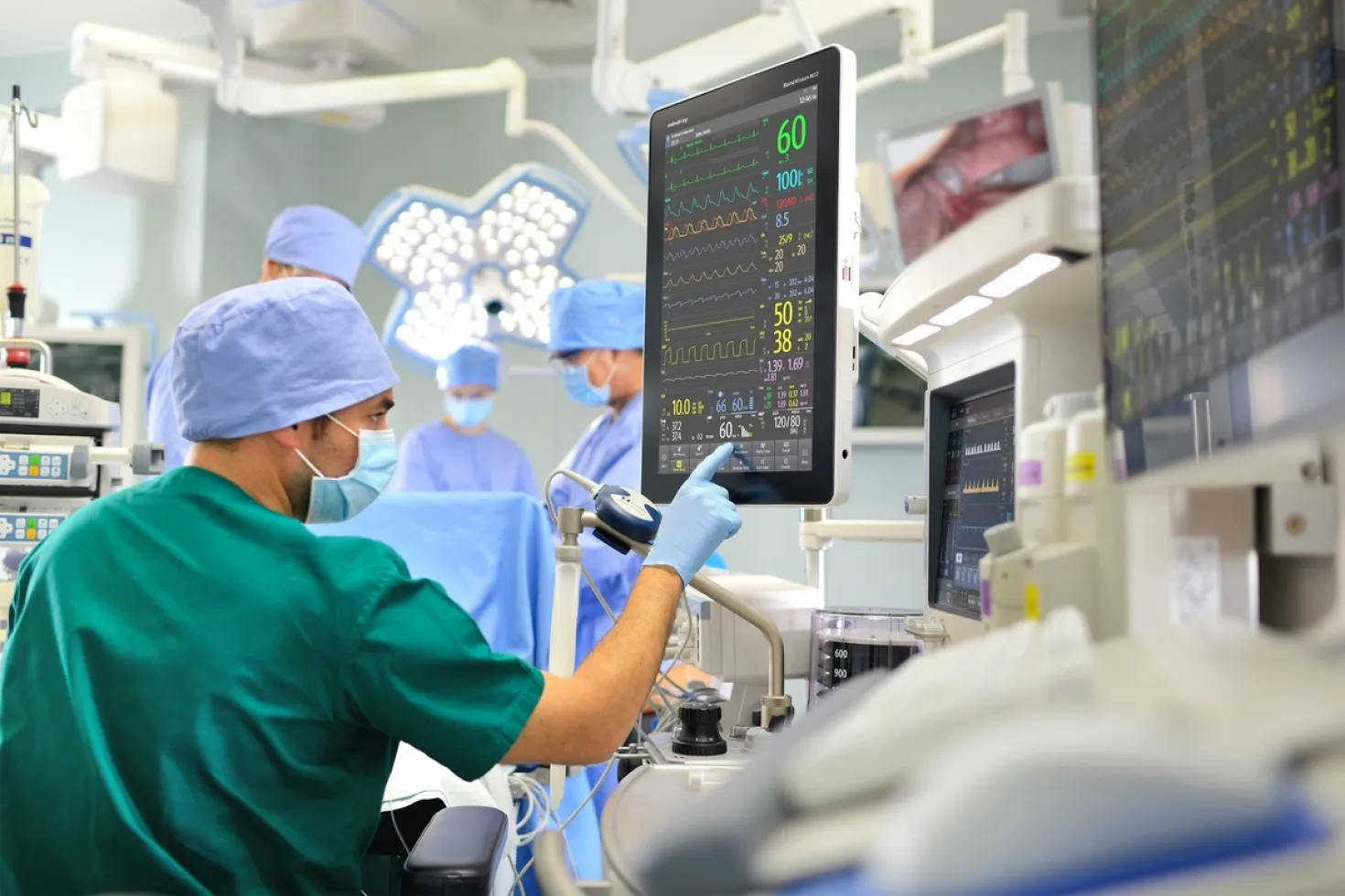 A male nurse checks a screen during a surgery