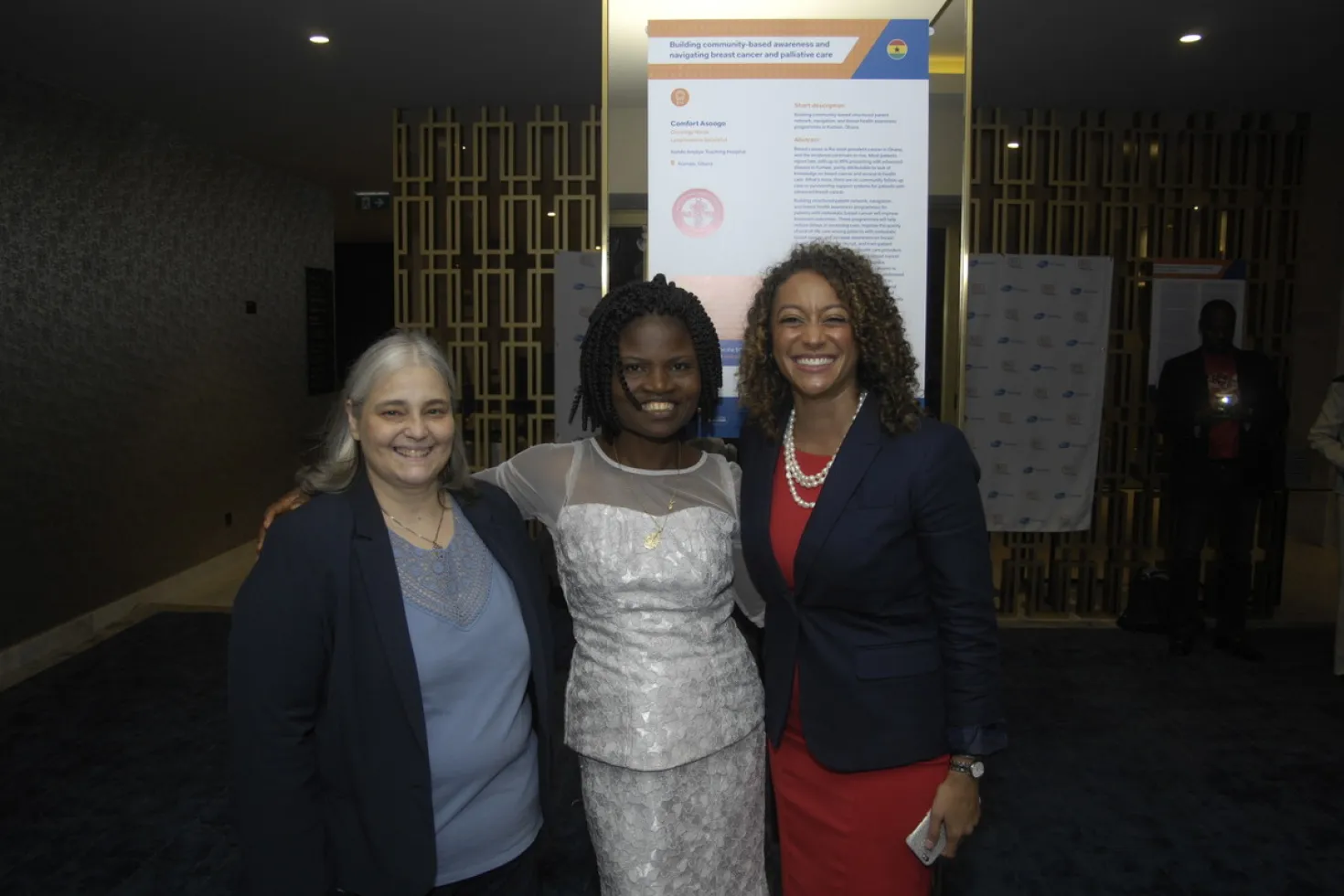 Group of women standing in front of abstract poster and smiling