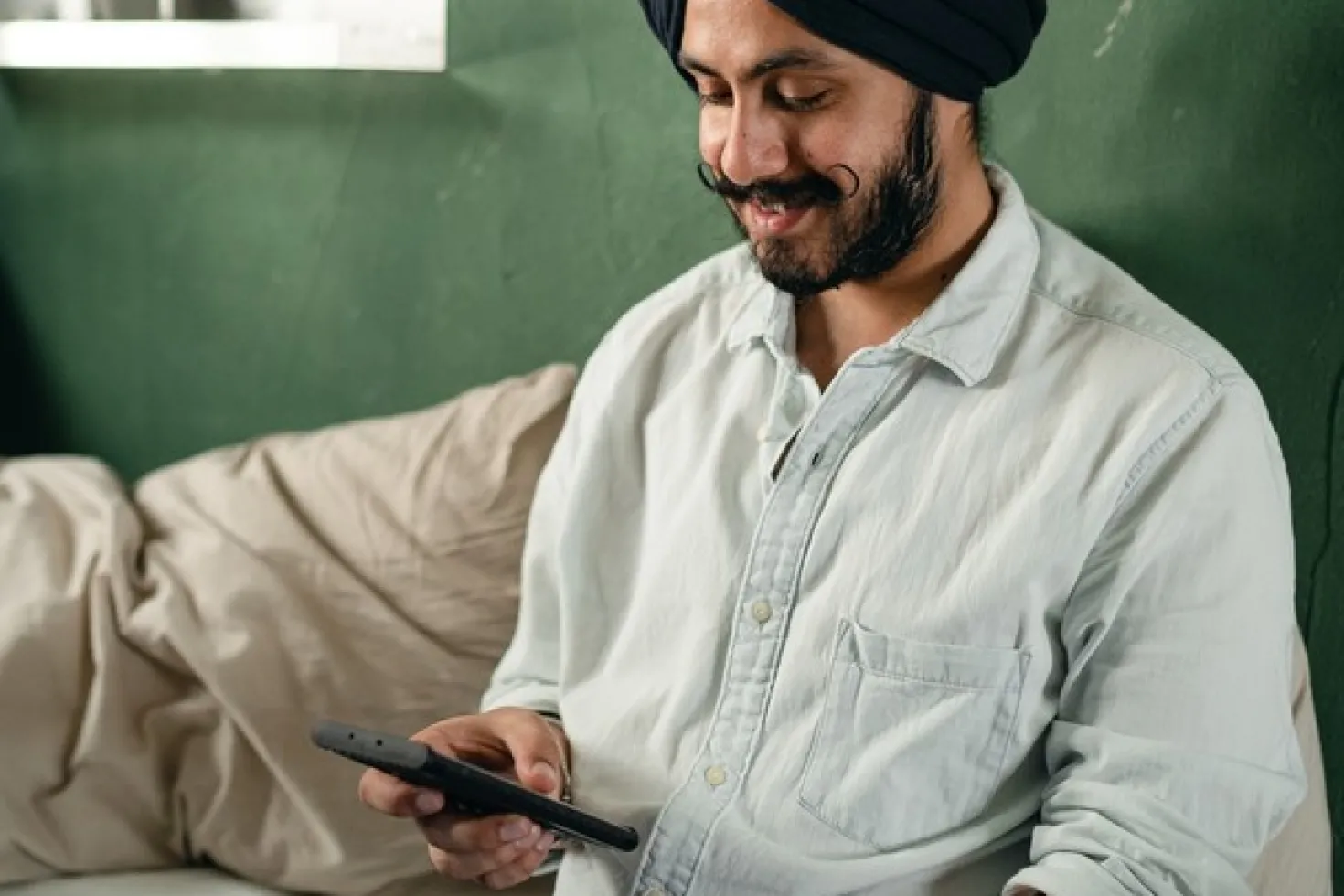Man with turban consulting his laptop and mobile phone