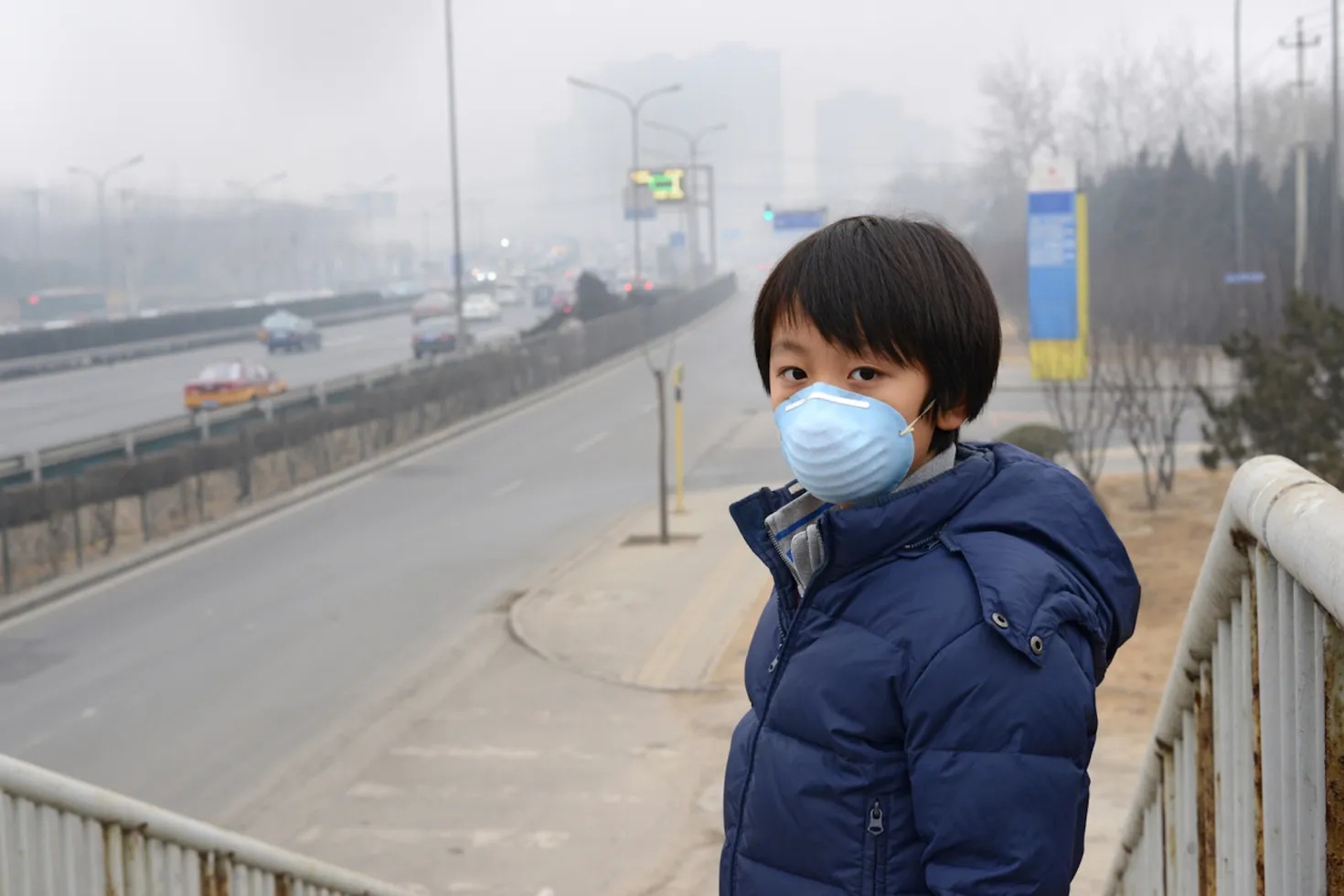 Asian child protects himself against air pollution by wearing mouth mask