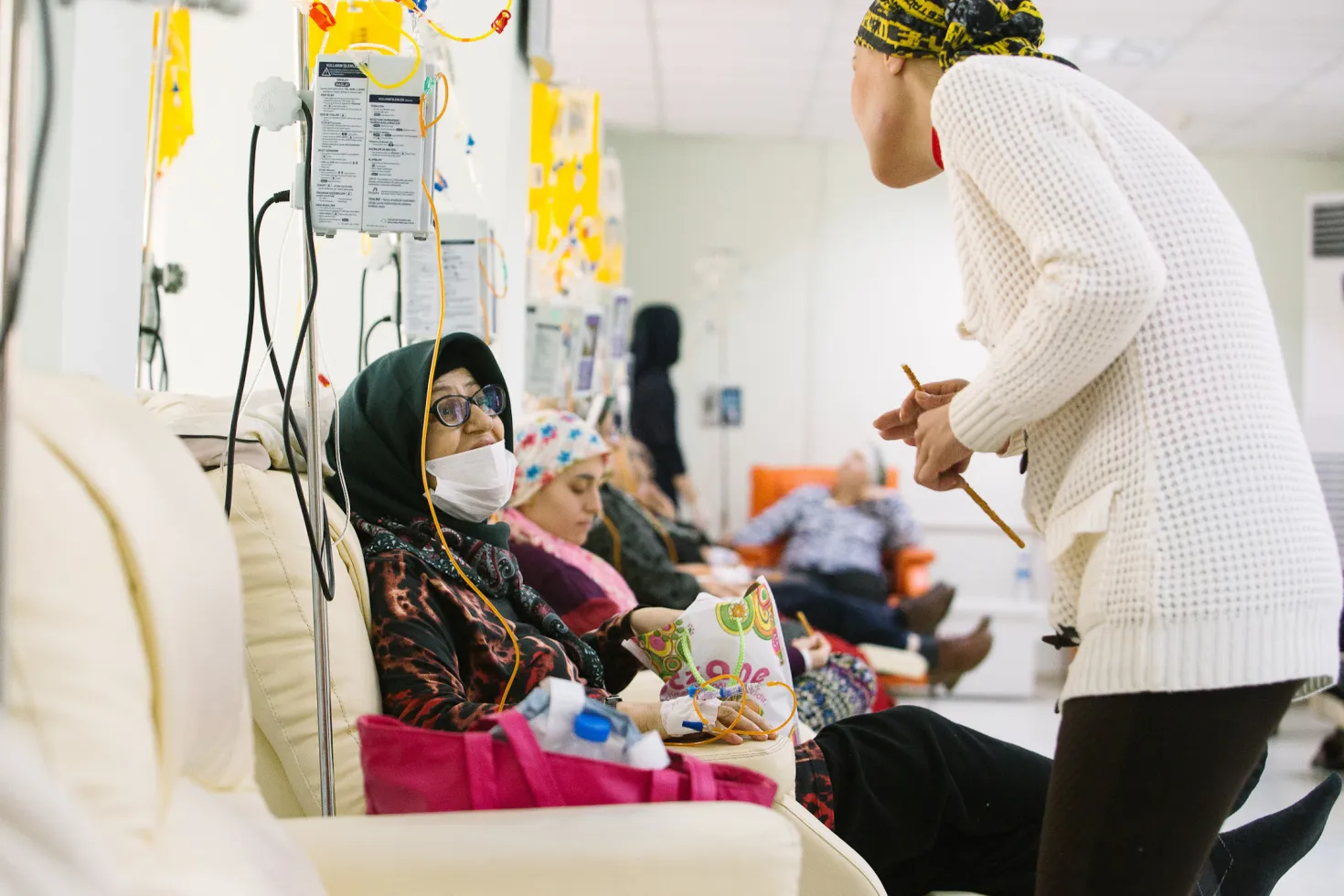 Women sitting in chairs in a row in a hospital in Turkey receiving cancer treatment