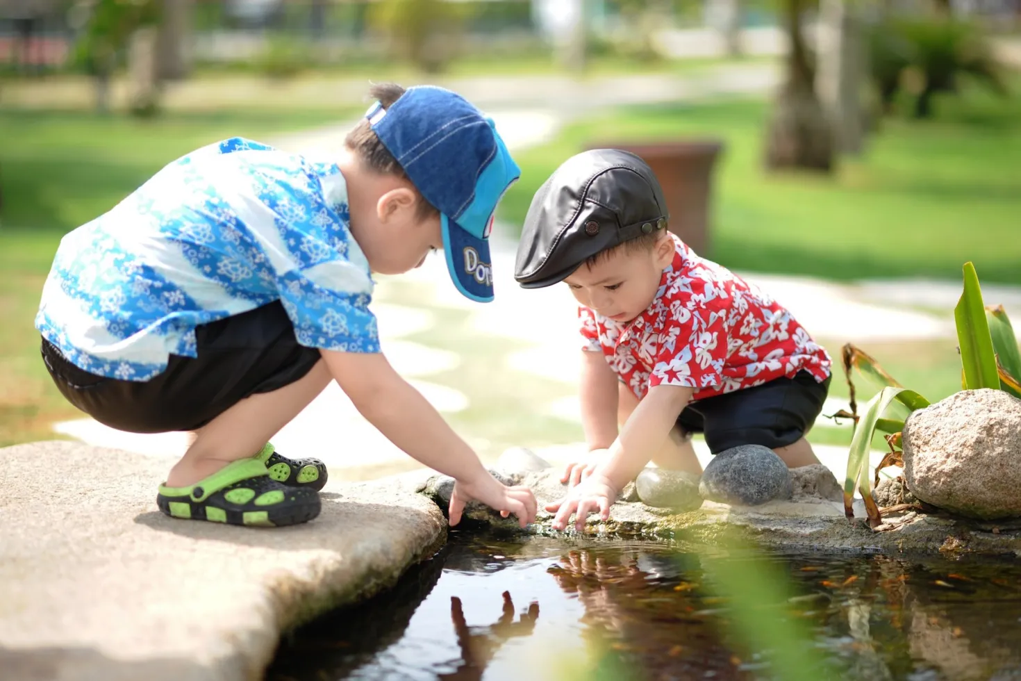 Two Asian children playing by a stream in a park
