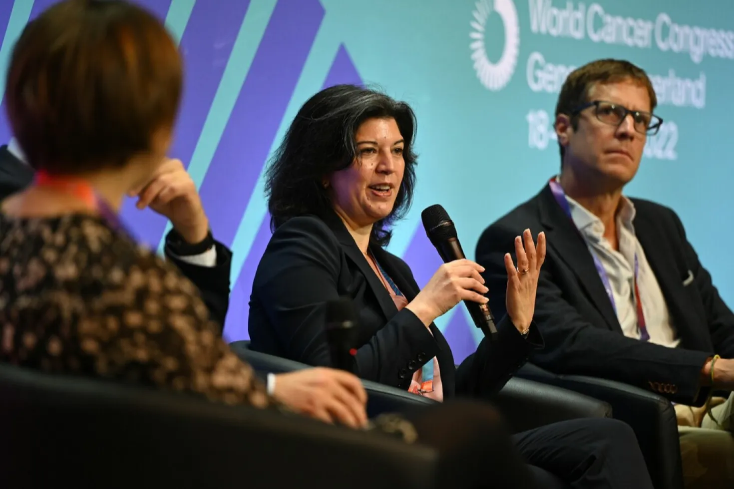 Female speaker with female panelist on her right and male panelist on her left