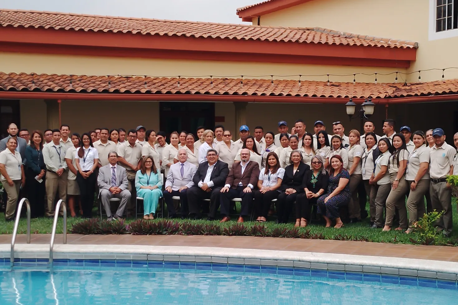 Staff of the the Asociación Salvadoreña para la Prevención del Cáncer (ASAPRECAN) standing in front of their offices, a house with a swimming pool