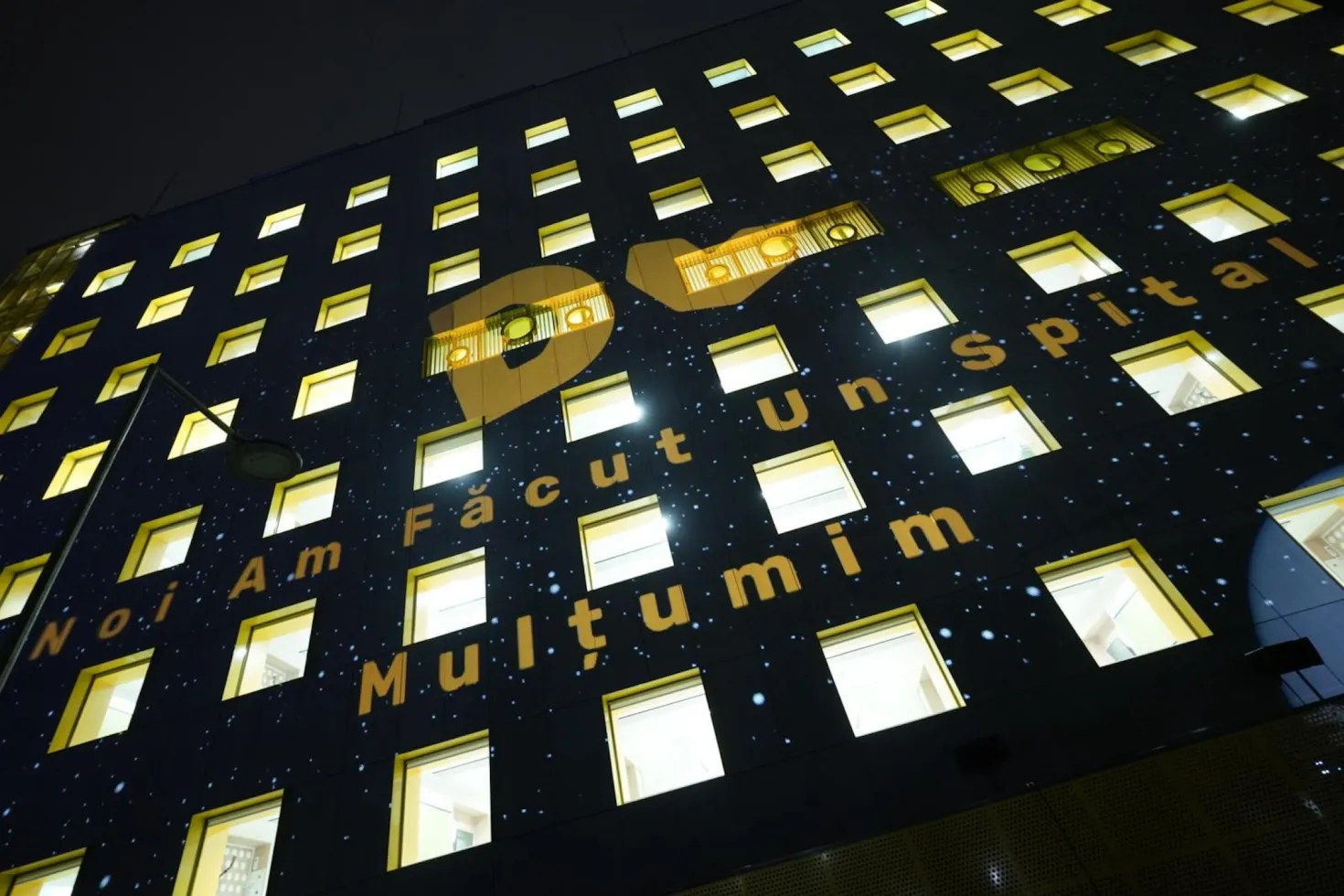 External façade at night of the children's hospital built thanks to Give Life in Roumania, with lights in all the windows.