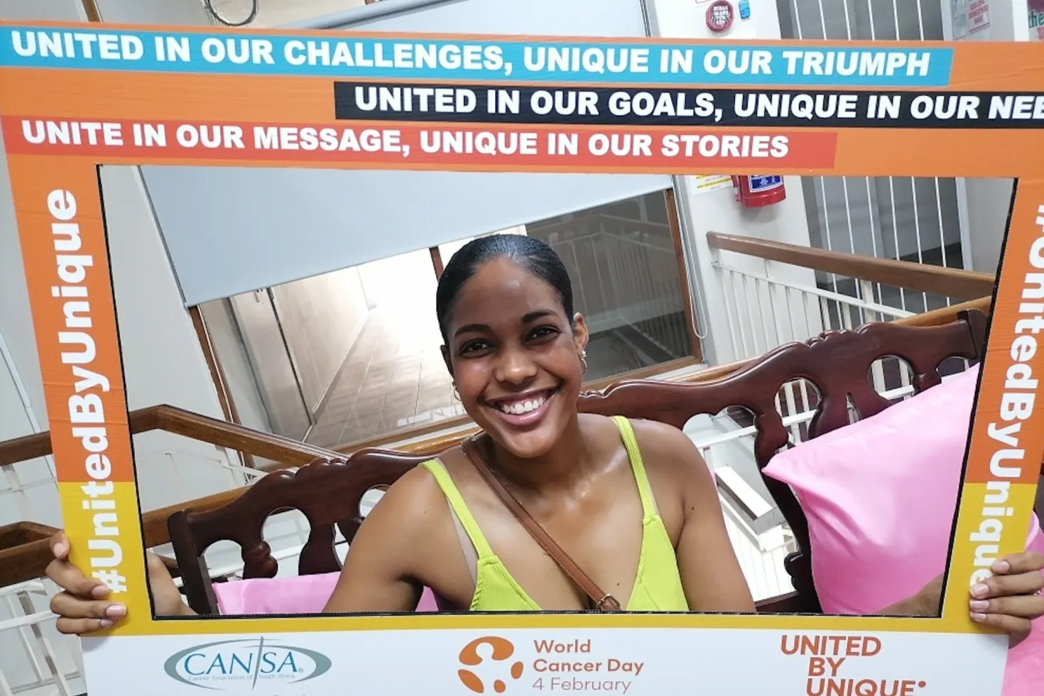 Black woman with branded United By Unique World Cancer Day poster material