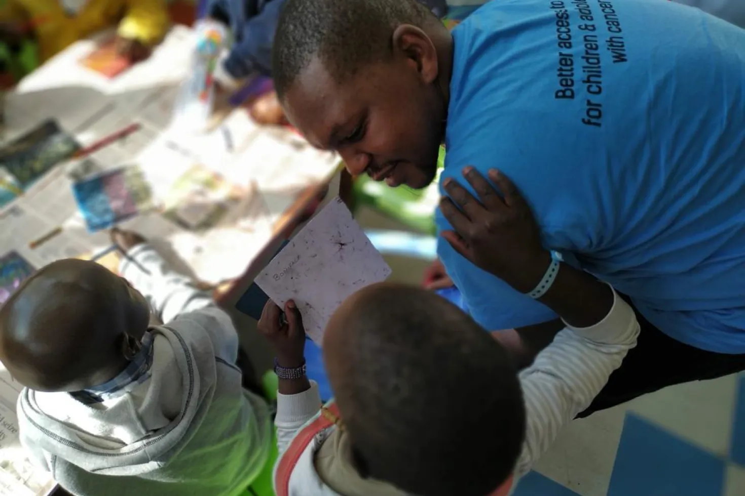 Black man in blue t-shirt engaging with children with cancer