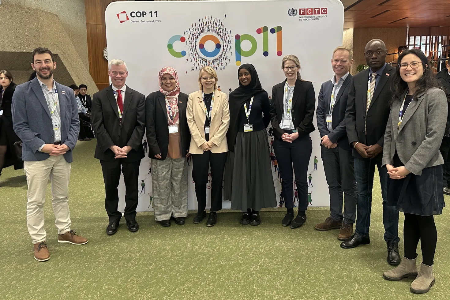 Diverse group of people posing in front of a branded COP11 backboard