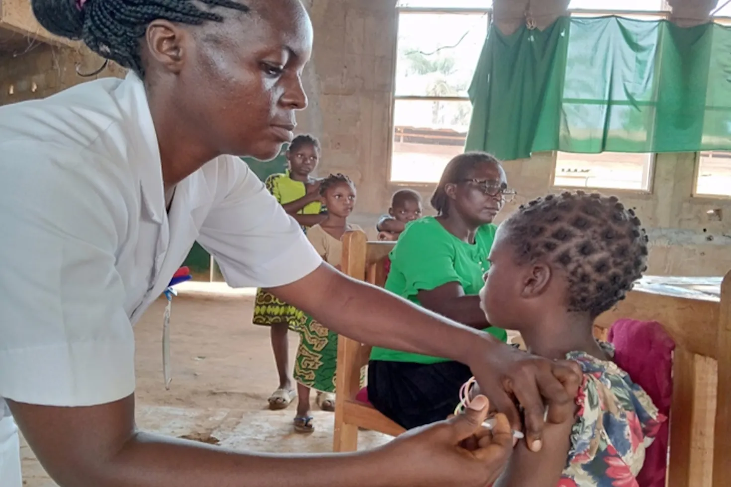 African nurse administering a vaccine to an African child