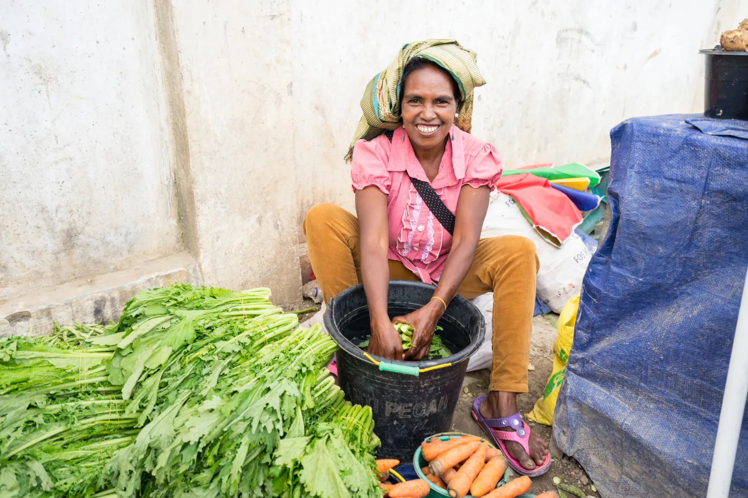 Timorese woman with headscarf and colorful traditional clothes at vegetable stall on the street