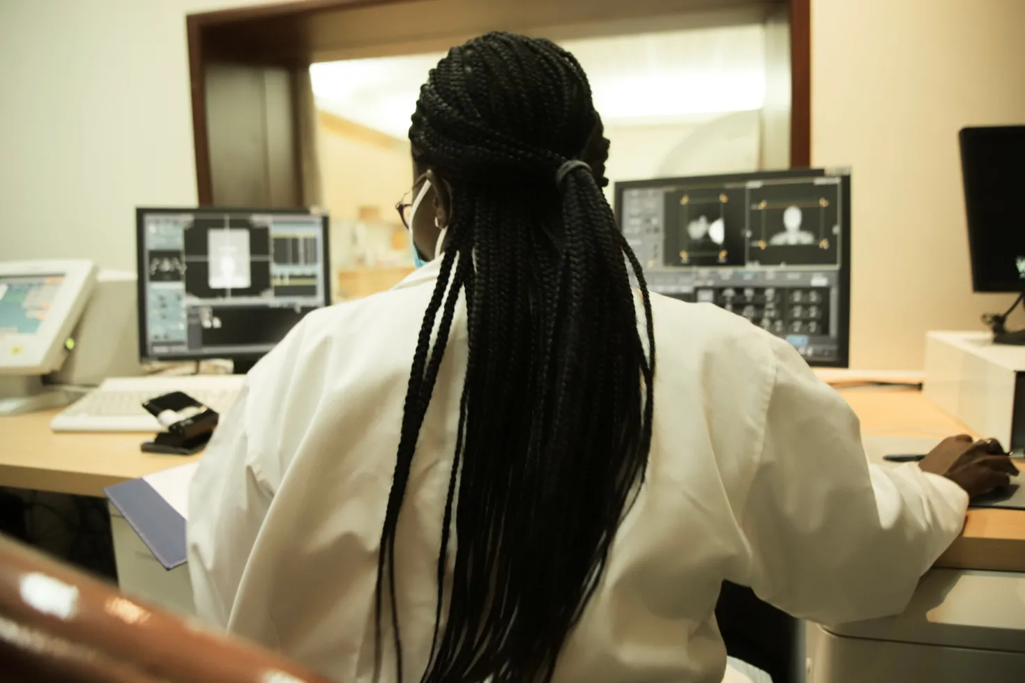 African woman in lab coat with long hair looking at scans on a computer