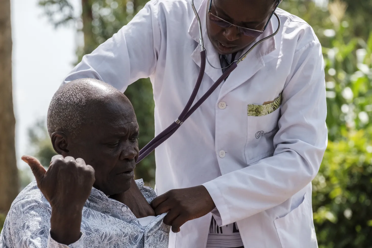 West Kenyan doctor examining an elderly male patient with a stethoscope