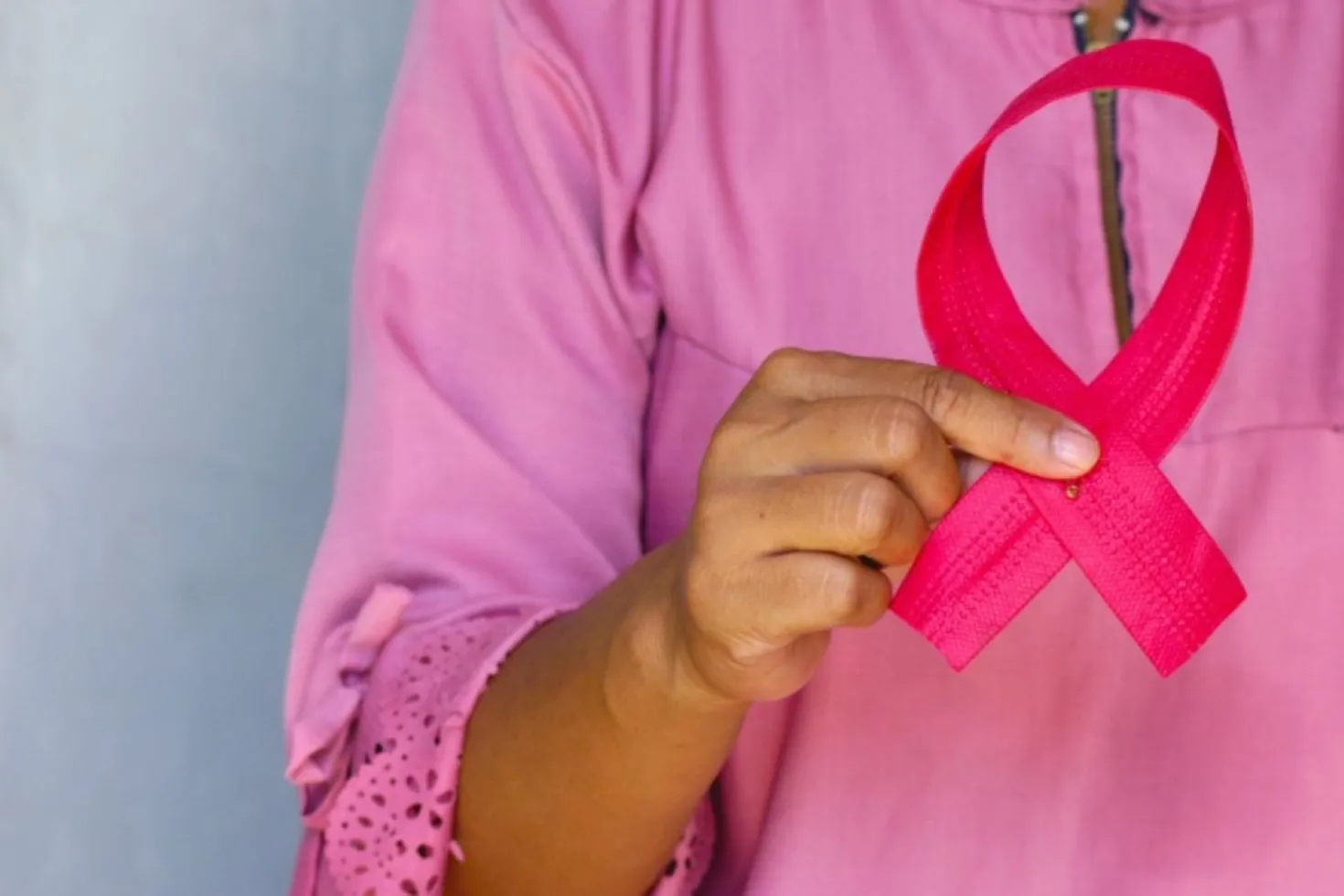 Woman dressed in pink holding a pink ribbon, symbolising breast cancer awareness month