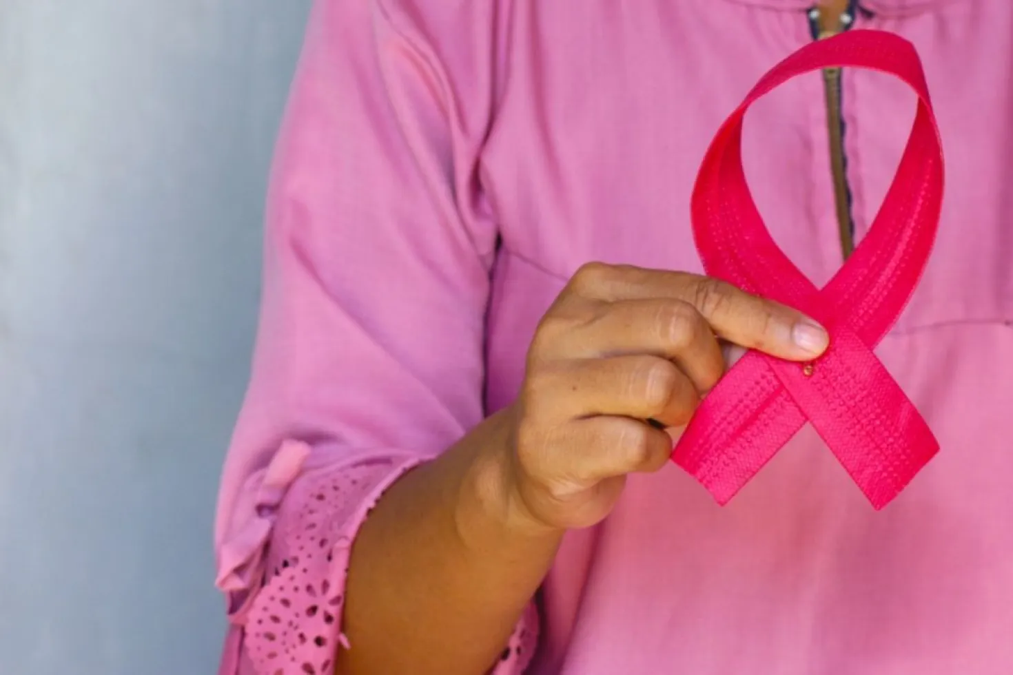 Woman dressed in pink holding a pink ribbon, symbolising breast cancer awareness month