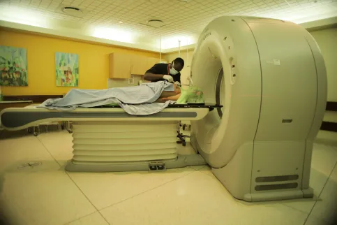 Medical worker assisting a patient to lie down before entering a MRI scanning machine