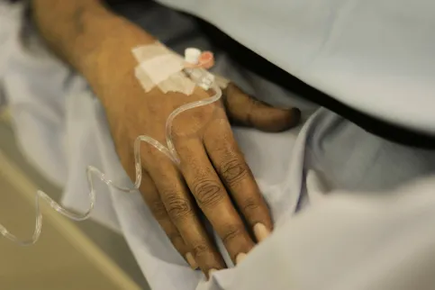 Close up of the hand of a black person on IV receiving treatment for cancer