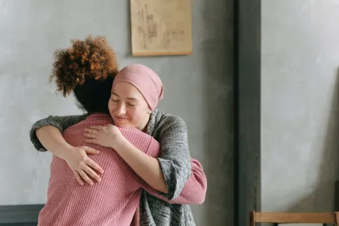 A woman embracing another woman wearing a headscarf