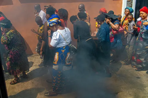 Crowd of men and women with hands to their faces as they walk through a heavily polluted area marked by black smoke