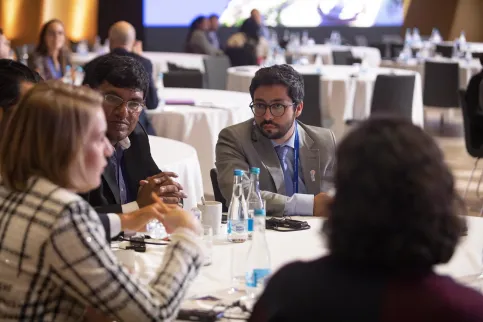 Four UICC Young Leaders, two women, two men, discussing at a round table during UICC World Cancer Leaders' Summit in Kazakhstan, 2019