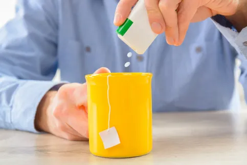 Man pours artificial sweetener containing aspartame into his tea. 