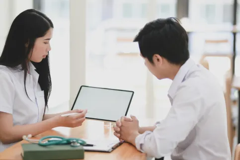 Asian man and woman healthworkers looking together at a patient file.
