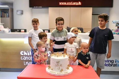 Children with cancer standing smiling around a cake that reads 'We love you'