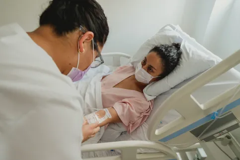 Woman lying in bed wearing a mask receiving IV treatment for cancer