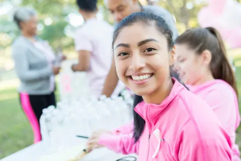 Young Asian woman wearing an pink jacket smiles to the camera