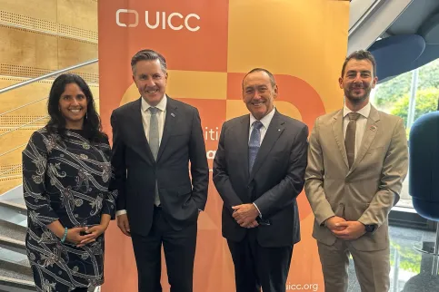 A woman and three men in suits stading in front of a UICC branded board