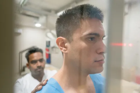 Young man with cropped hair being examined for a chest x-ray