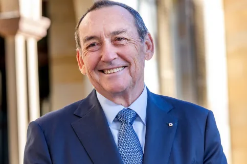 Headshot of Prof. Jeff Dunn, AO, President of UICC (2022-2024), in blue suit and tie, clasping hands in front of him