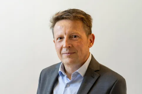 Headshot of a middle aged white man wearing shirt and suit, no tie