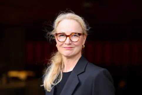 Headshot of Scandinavian woman in dark suit, shoulder-length blond hair, wearing glasses