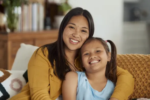 Mother with daughter sitting on a couch smiling