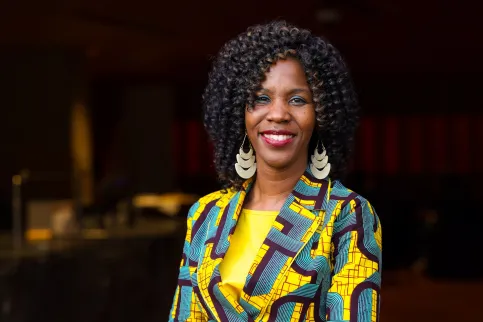 Dr Miriam Mutebi, UICC Board Member, an African woman in green and yellow clothing