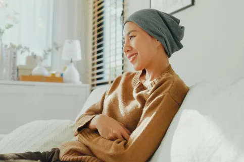 Asian woman with a headscarf smiling, seated on a sofa