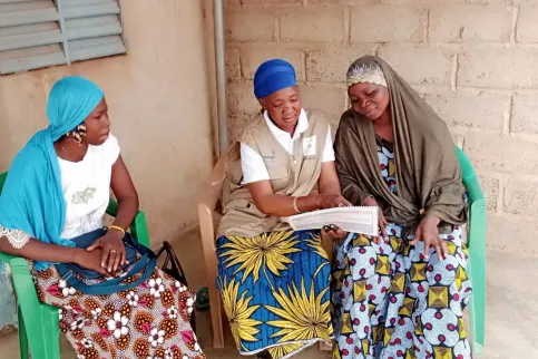 An African woman speaking to two others about health