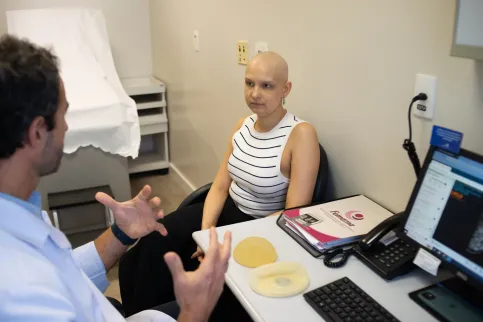 Woman with no hair speaking to a doctor