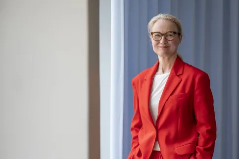 2/3 body shot of middle-age white woman wearing red orange suit with white t-shirt