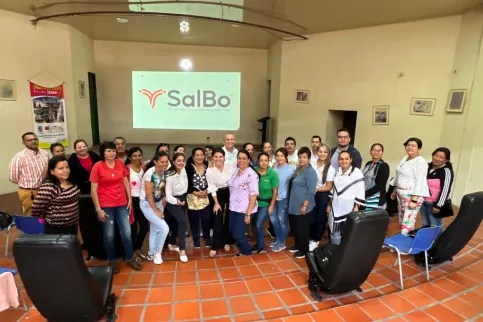 Group of people in a large room in front a screen featuring the word "SalBo" a cancer organisation