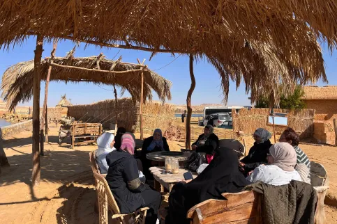 Group of Middle Eastern women sitting at a table in a desert village