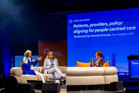 Three people on stage at a panel event on people-centred cancer care