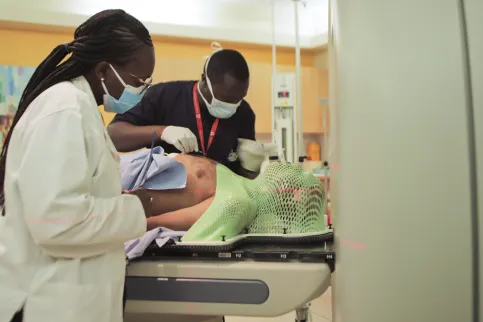 Male and female medical workers assisting a patient to lie down before entering a MRI scanning machine