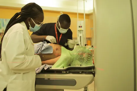 Male and female medical workers assisting a patient to lie down before entering a MRI scanning machine
