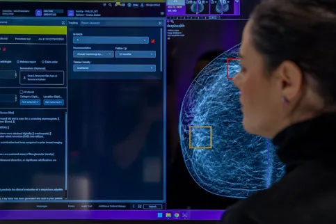 Woman wearing black polo neck sweater looking an AI analysis of a breast cancer scan